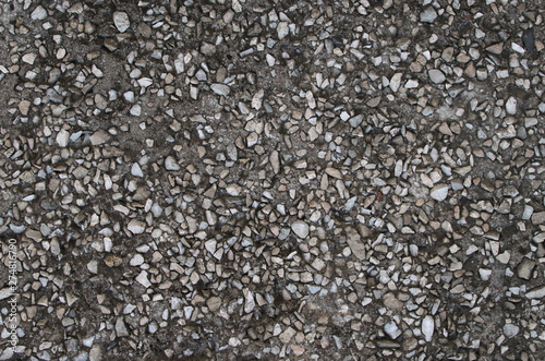 Inclusions of gray stone pebbles in asphalt and cement