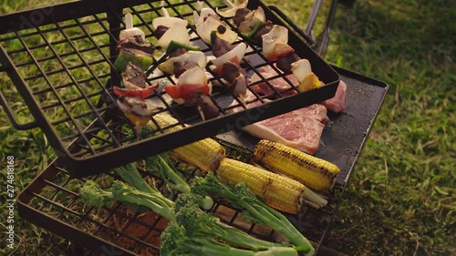 Turning vegetables and meat over a fire BBQ in the afternoon glow photo