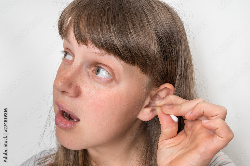 Woman cleans her ears with cotton swab Woman cleans her ears with cotton swab
