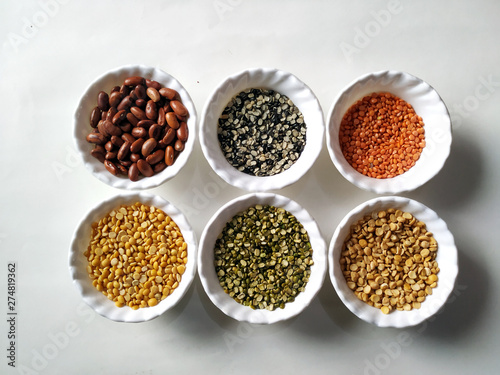 Uncooked pulses,grains and seeds in White bowls over white background. selective focus