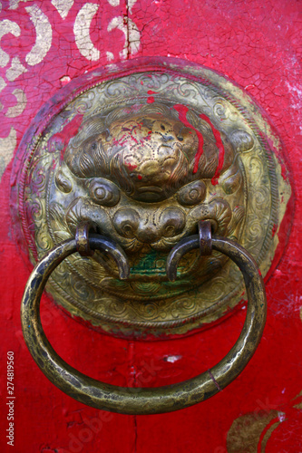 Ancient lion head door knocker on a red door in Tovkhon Monastery, Ovorkhangai Province, Mongolia. UNESCO World Heritage Site. photo