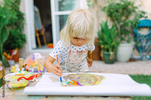 Foto Little cute girl painting in the garden and mixing different colors
