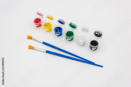 Colorful paints and brushes quietly placed on a white background