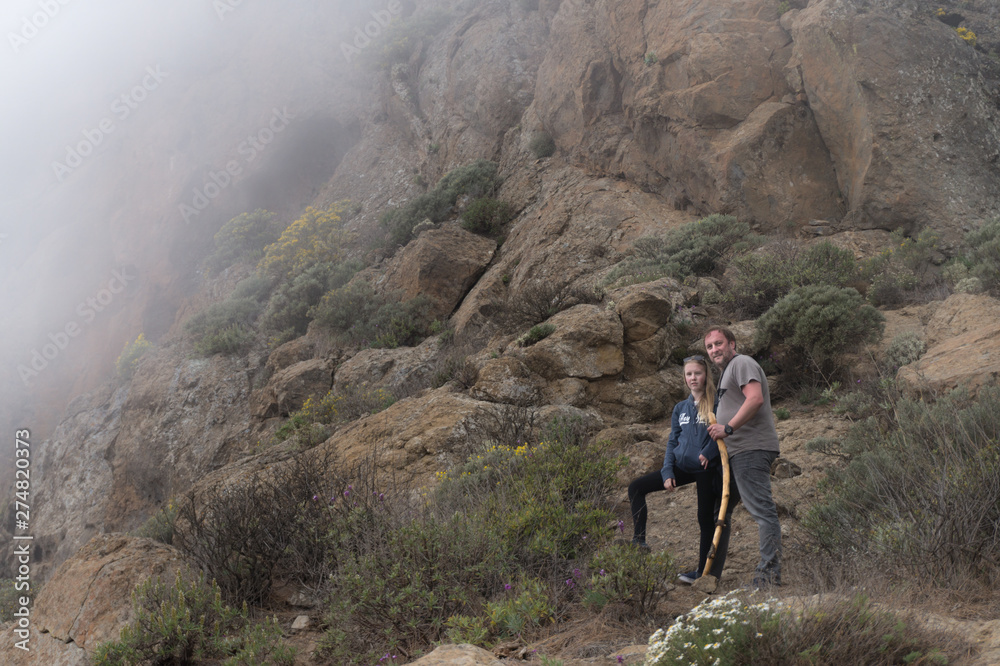 Men and teenage girl hiking in the mountains in foggy day Men and teenage girl hiking in the mountains in foggy day
