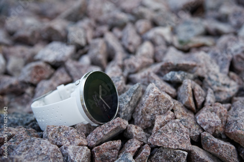 Sport watch for triathlon on the granite gravel. Smart watch for tracking daily activity and strength training.