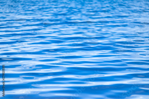 Water surface. Background image. The concept of recreation at the sea, by the river or lake. Shades of blue, minimalism. The texture of the water surface.