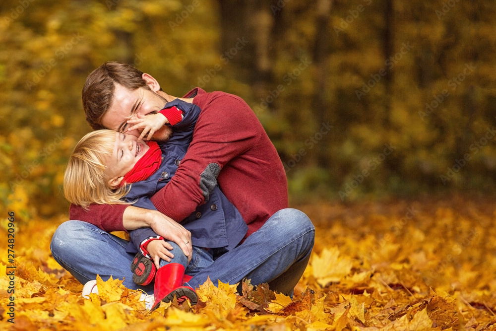 Father and daughter hug and laugh in the autumn park. Father and daughter hug and laugh in the autumn park.