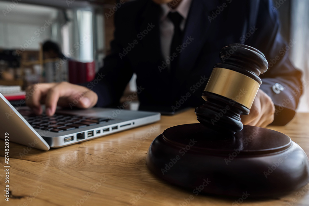 justice and law concept.Male judge in a courtroom the gavel, working with digital tablet computer on wood table. justice and law concept.Male judge in a courtroom the gavel, working with digital tablet computer on wood table.