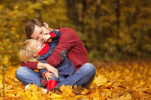 Father and daughter hug and laugh in the autumn park.