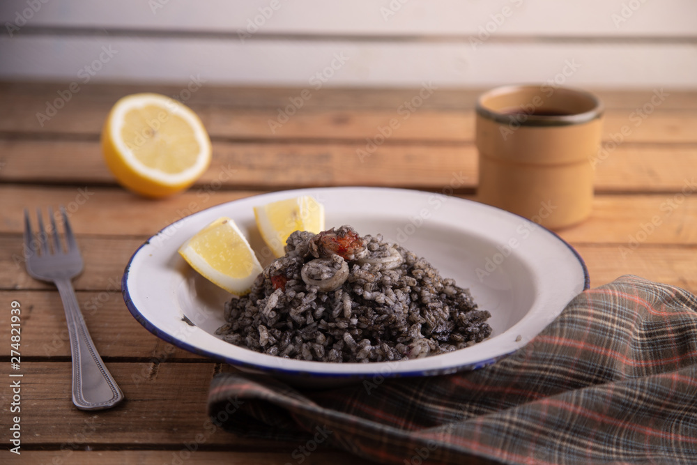 Plate of black rice with squid and prawns or Valencian black paella Plate of black rice with squid and prawns or Valencian black paella