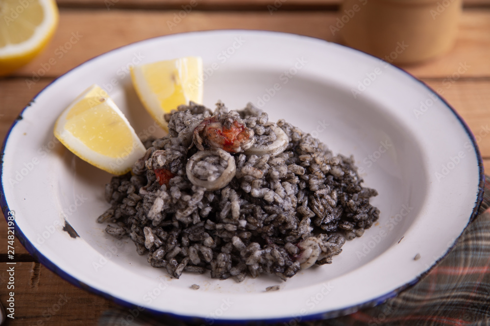 Plate of black rice with squid and prawns or Valencian black paella Plate of black rice with squid and prawns or Valencian black paella