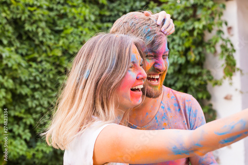 Festival holi, people concept - young couple taking selfie in colourful dirty clothes