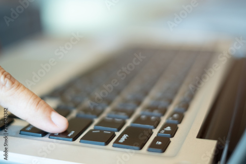 finger push the enter button of notebook keyboard. selective, soft focus