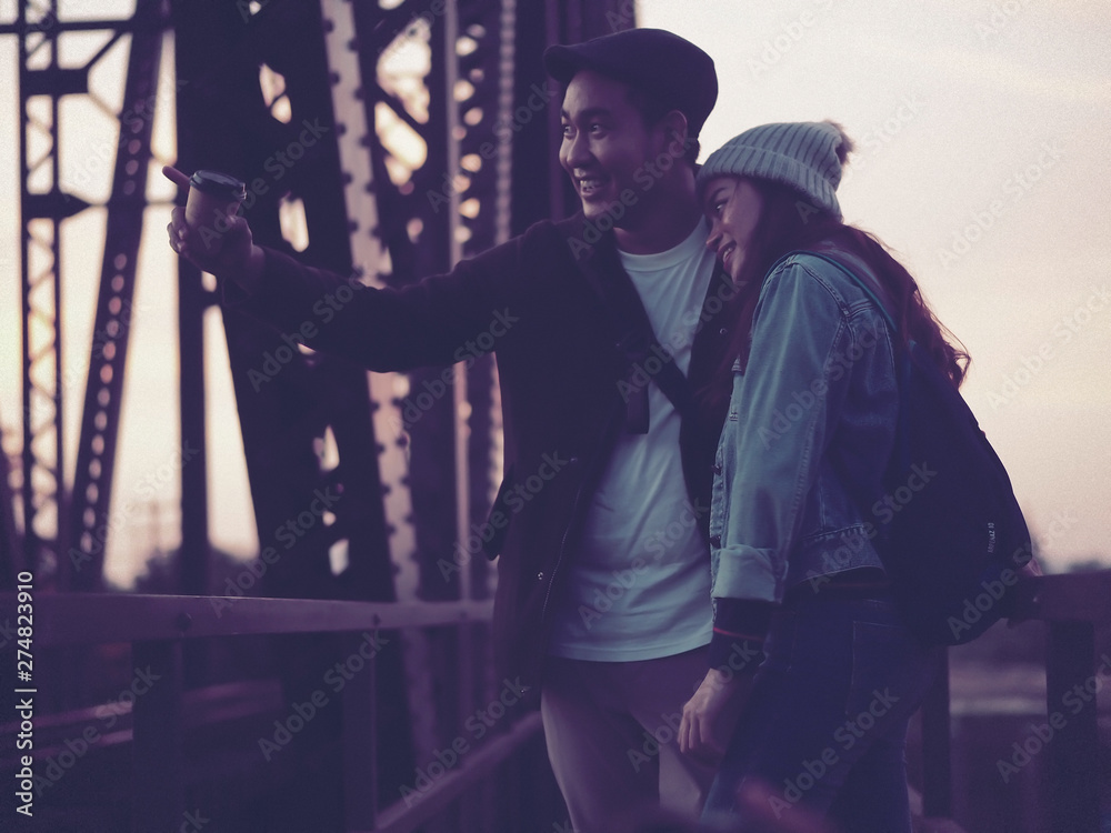 Happy Asian tourist couple drinking takeaway coffee cup with black iron bridge background. Happy Asian tourist couple drinking takeaway coffee cup with black iron bridge background.