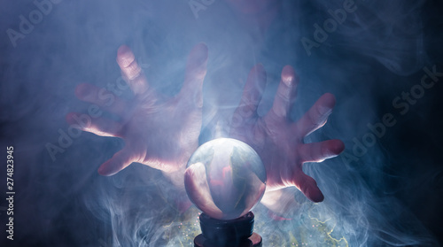 Foto The hands of a fortune teller and a glass ball can be seen against a black background