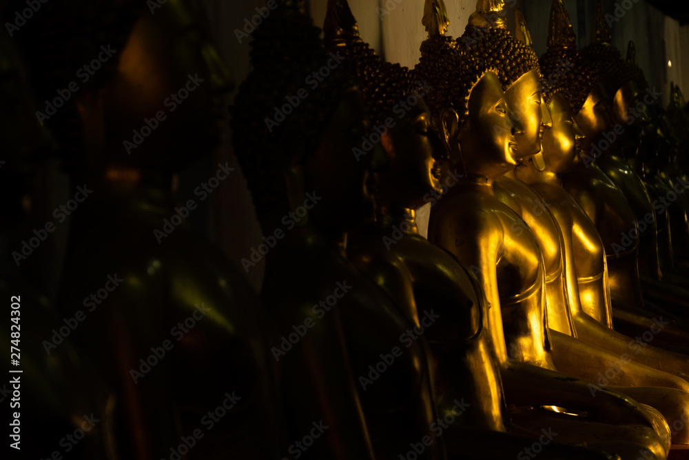 Naklejka premium close up row of golden buddha statue in the light and shadow of sun at Wat Pra Sri Mahathat temple, Phitsanulok province, Thailand