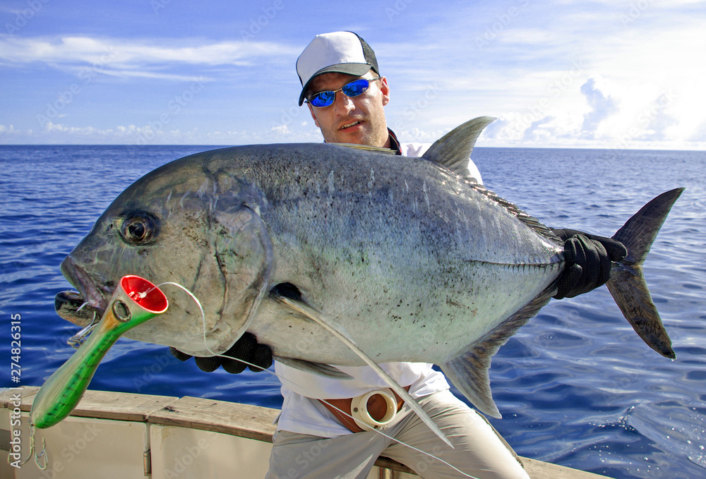 Deep sea fishing, catch of fish, big game fishing, boat fishing, lure  fishing, sea fishing. Fisherman holding a big Trevally jack. Stock Photo