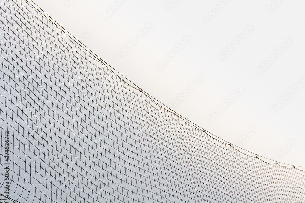 High fence made of white mesh on football field. High fence made of white mesh on football field.