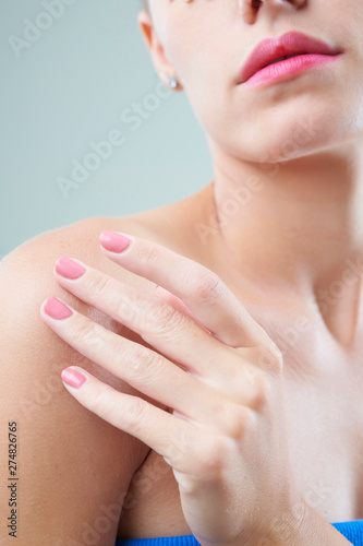 Close-up image of woman applying moisturizing body lotion on her shoulder