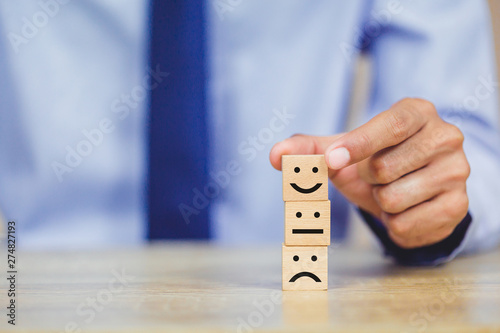 customer pressing smiley face emoticon on wood cube, Service rating, satisfaction concept.