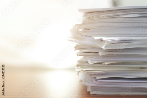 Paper stack on desk related to business functions. Paper-related work on the table.