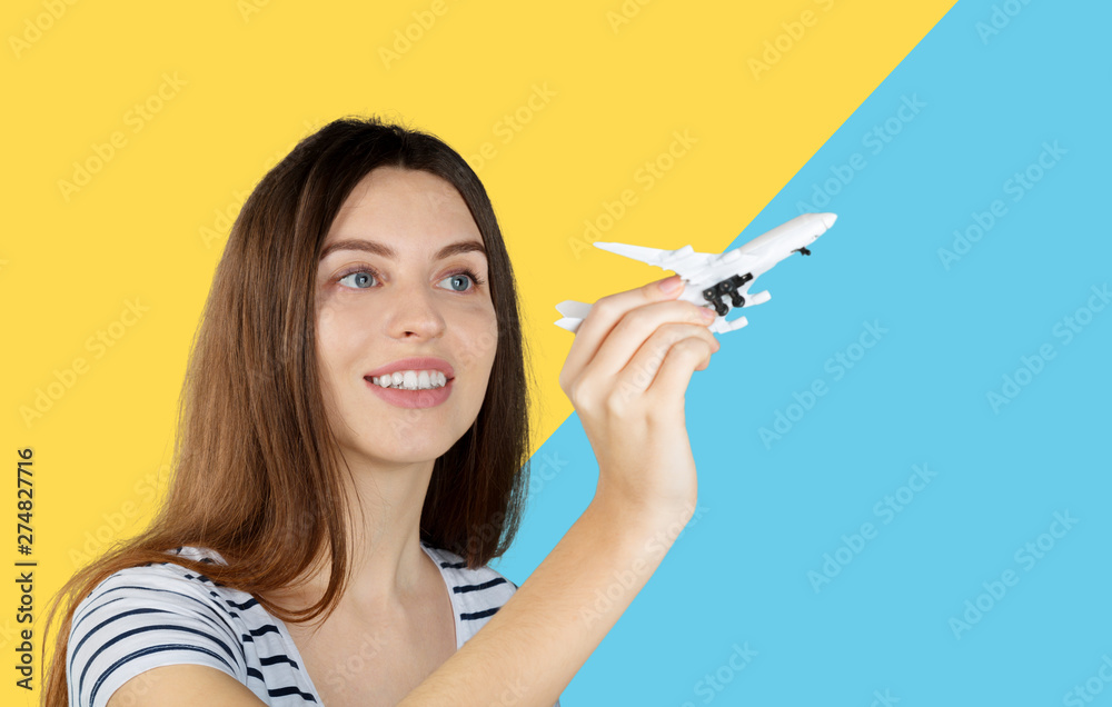 Young pretty woman with a wooden toy plane. Transportation or travel concept Young pretty woman with a wooden toy plane. Transportation or travel concept