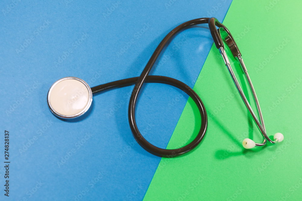 A stethoscope is laying on a green and blue surface A stethoscope is laying on a green and blue surface