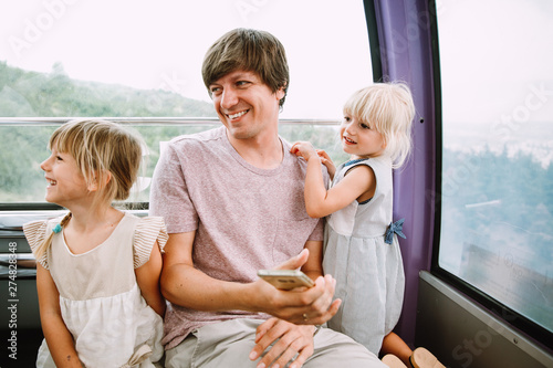 Young father with two little daughters in the cabin of a Ferris wheel in Tbilisi