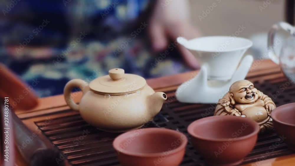 A beautiful set for the tea ceremony stands on a small wooden table. In the kettle pour boiling water A beautiful set for the tea ceremony stands on a small wooden table. In the kettle pour boiling water