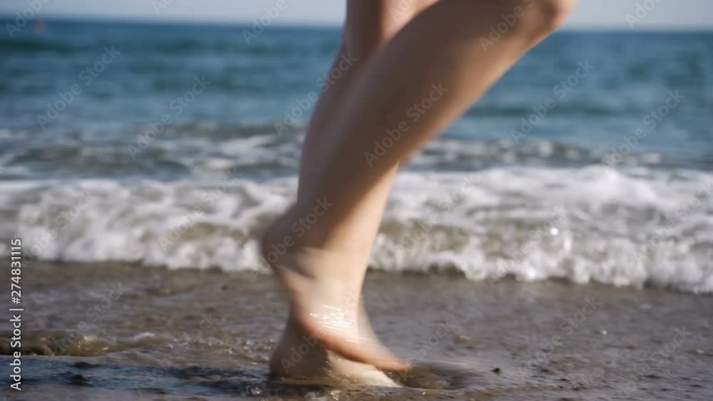 Close up shot of the feet of a woman who walks barefoot on wet sand Close up shot of the feet of a woman who walks barefoot on wet sand