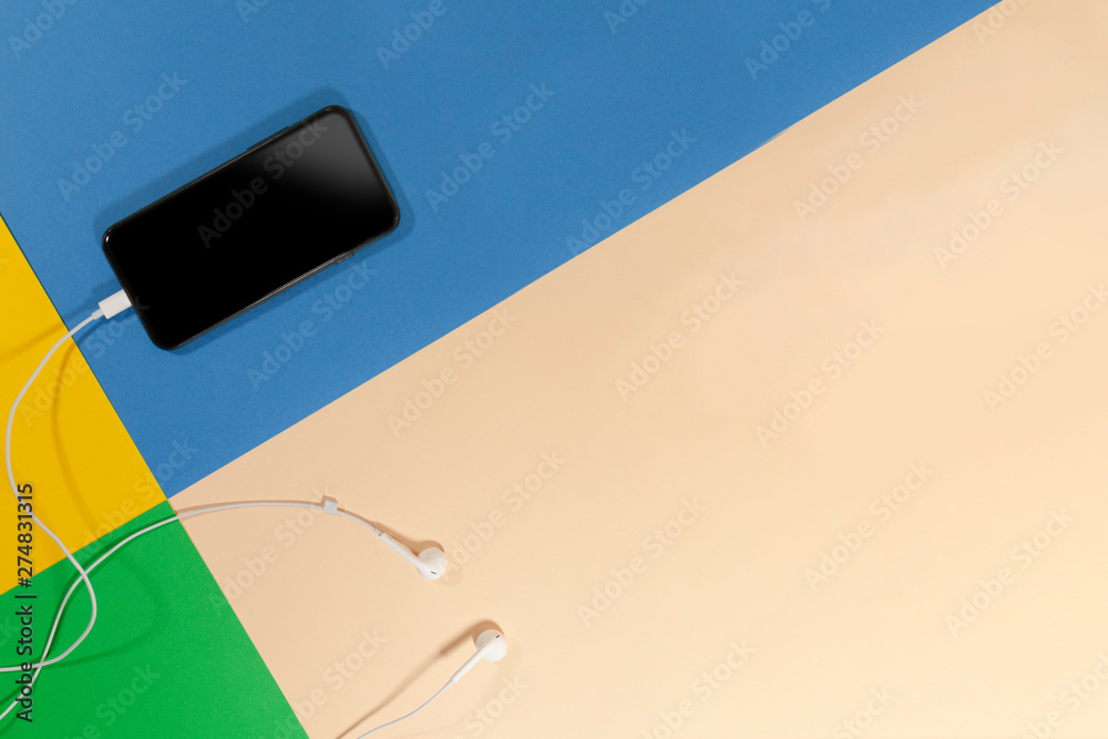 Obraz premium A cellphone and headphones are laying on a multicolored surface