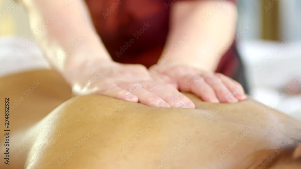 Close up of female masseur hands doing massage on moisturized female back Close up of female masseur hands doing massage on moisturized female back