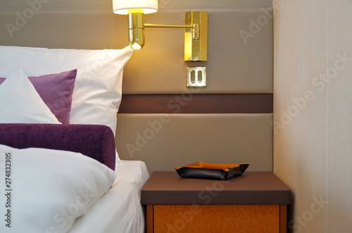 Detailaufnahme Bett und Nachttisch mit Doppelbett und Lampe in Suite auf Luxus-Kreuzfahrtschiff photo