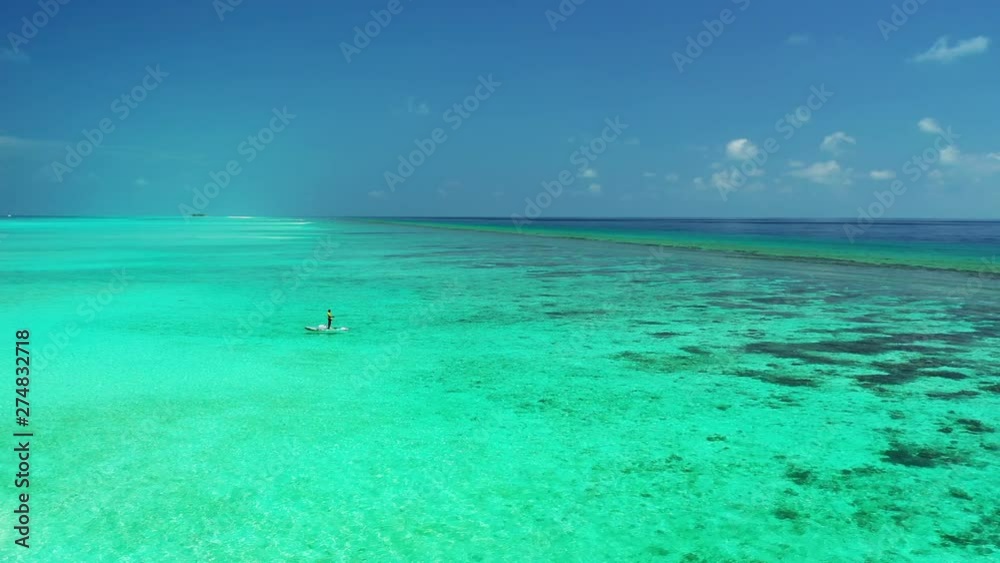Aerial view of turquoise, green water under a blue sky. A reef in the distance. In the Maldives. Aerial view of turquoise, green water under a blue sky. A reef in the distance. In the Maldives.
