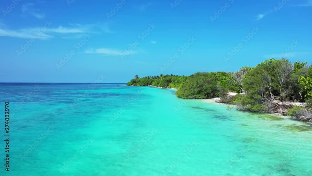 Aerial view of a flight sideways away from a tropical island forested by trees. Turquoise water next to it. In Jamaica. Truck left, dolly in Aerial view of a flight sideways away from a tropical island forested by trees. Turquoise water next to it. In Jamaica. Truck left, dolly in