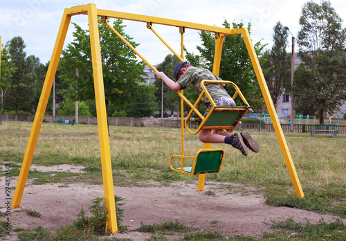 child riding a swing on the playground in the city