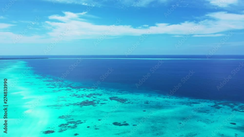 Aerial view of the blue sea that turns into turquoise under a blue cloud sky. In the Philippines. Dolly out. Aerial view of the blue sea that turns into turquoise under a blue cloud sky. In the Philippines. Dolly out.