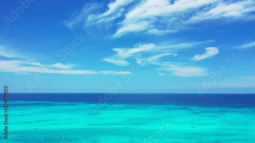 cirrostratus clouds in a blue sky abovethe turquoise blue Philippine Sea. Soft pan right. photo