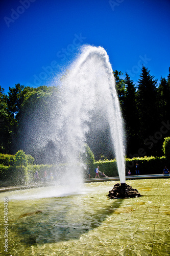 fountain on the lake on a background of green park under a blue sky