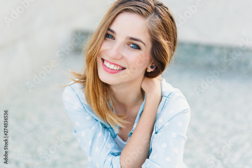 Happy young Caucasian woman demonstrating perfect teeth over light gray blurred background