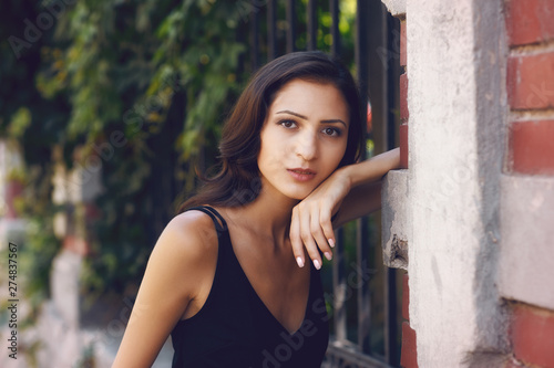 Open portrait of a young beautiful girl in the city . Woman wearing elegant black dress