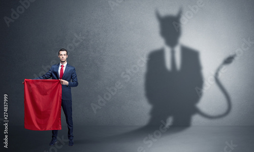 Businessman standing with red cloth in his hand and devil shadow on the background
