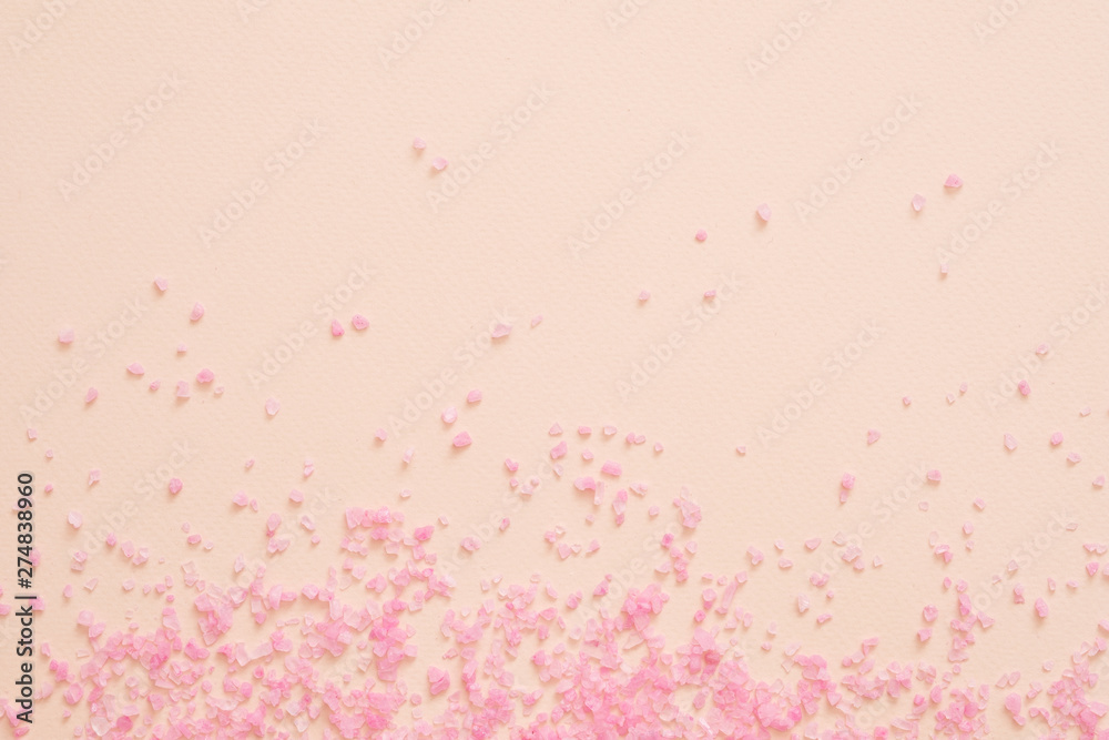 Spa therapy. Pink bath salt crystals scattered over peach surface. Abstract background. Copy space. Spa therapy. Pink bath salt crystals scattered over peach surface. Abstract background. Copy space.