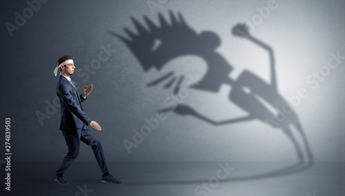 Young karate man fighting with a big black scary shadow 