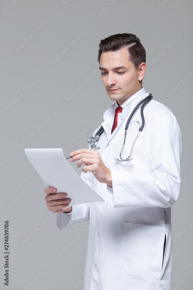 Portrait of young doctor in white uniform with stethoscope holding folder Portrait of young doctor in white uniform with stethoscope holding folder