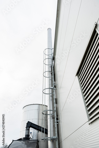 Chimney sweep cleaning a chimney standing balanced on the apex of a house roof lowering equipment down the flue