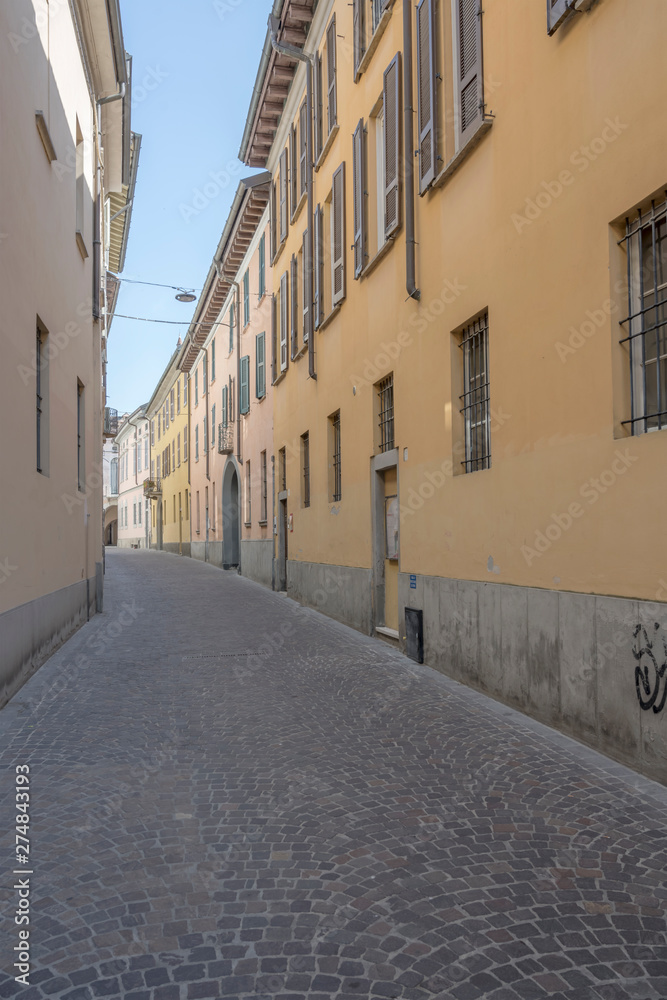 cityscape with old houses on cobbled street, Crema, Italy