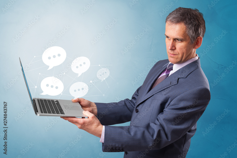 Man holding laptop with a few speech bubble symbols
Man holding laptop with a few speech bubble symbols