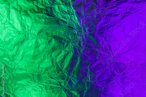 Violet green deformed background made of neon lights foil. Trendy duotone texture