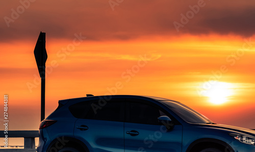 Fototapeta Naklejka Na Ścianę i Meble -  Side view of blue SUV car with sport and modern design parked on concrete road at sunset. Hybrid and electric car technology. Road trip. Automotive industry. Luxury car with beautiful sunset sky.
